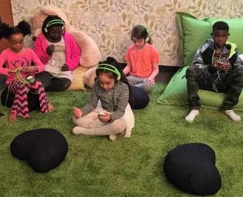 Five children sit, listen to music, and meditate in the Regence Club Peace Room