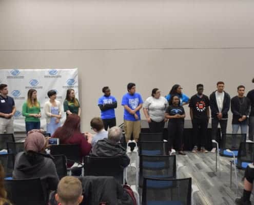 Graduating seniors stand at front of room as they are recognized