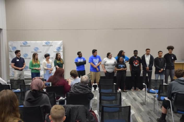 Graduating seniors stand at front of room as they are recognized