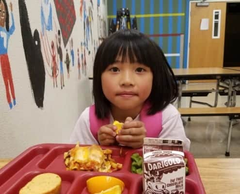 Youth member eats meal in Kids Cafe at Inukai Family Club