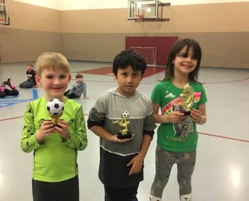 Three 1st-6th grade Club members holding Indoor Soccer Trophies