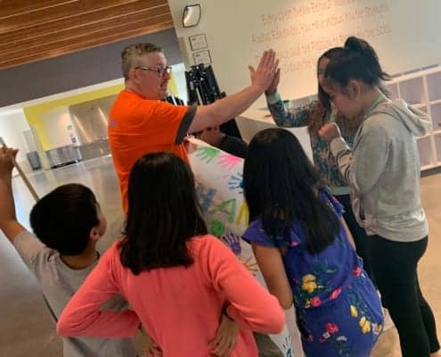 Youth at Rockwood give long-time volunteer Mr. Scott a "thank you" banner as he gives one of them a high five.
